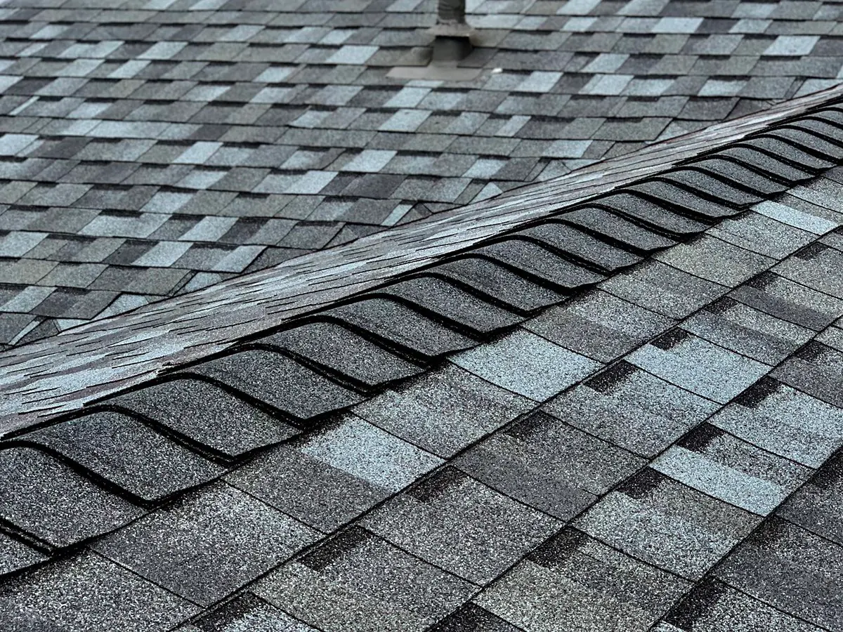 Close view of layered ridge-cap shingles and a vent-pipe penetration