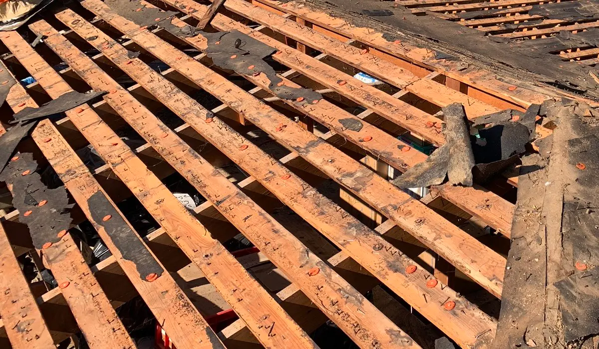 Roof tear-off exposing spaced wood decking and remnants of old felt underlayment