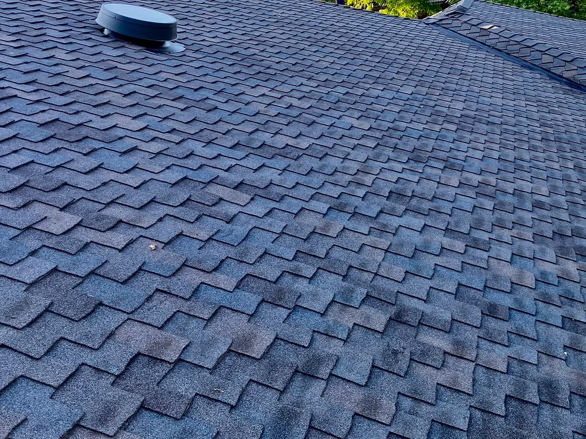 Round attic vent in a field of dark asphalt shingles